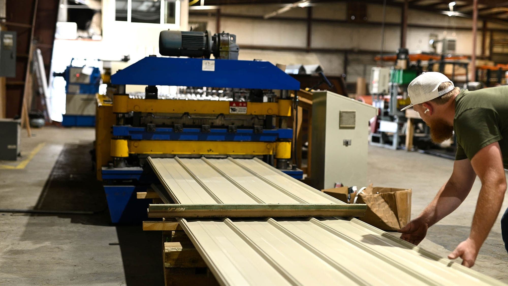 Operator guiding a finished metal panel off the roll-former at the South Boston, Virginia mill